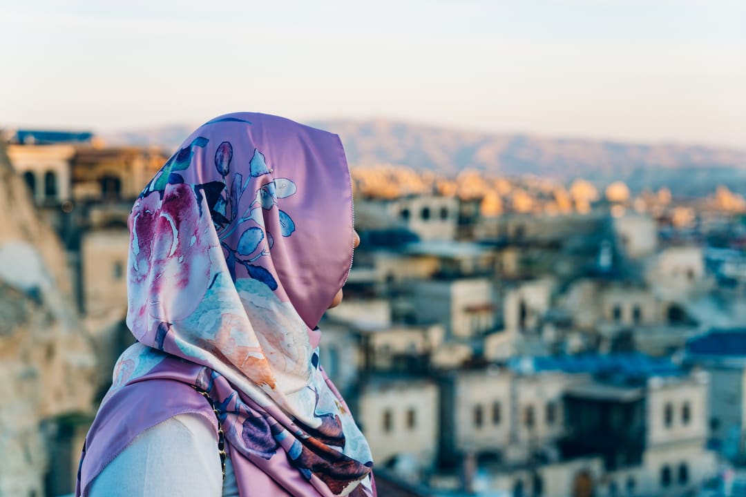 A pink and blue LE Bohemian floral print satin scarf seen from behind, with the rooftops of Göreme, Cappadocia in the background