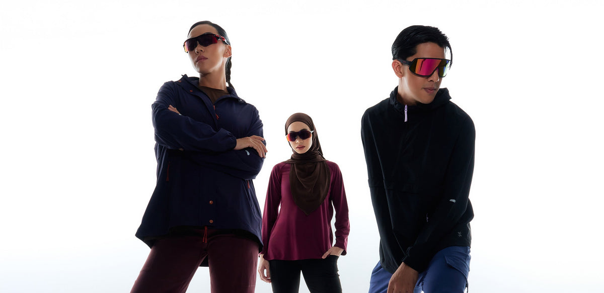 A woman in a dark brown sport hijab and plum long-sleeve top stands between two runners in sports sunglasses and running jackets