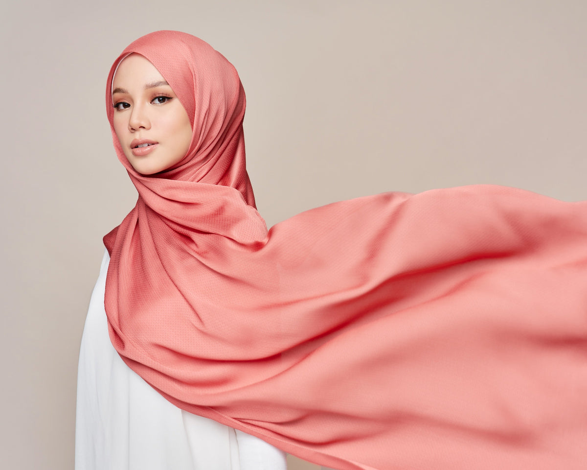 A woman in a coral satin shawl lets the long end flow out to the side, showing the fabric's soft sheen