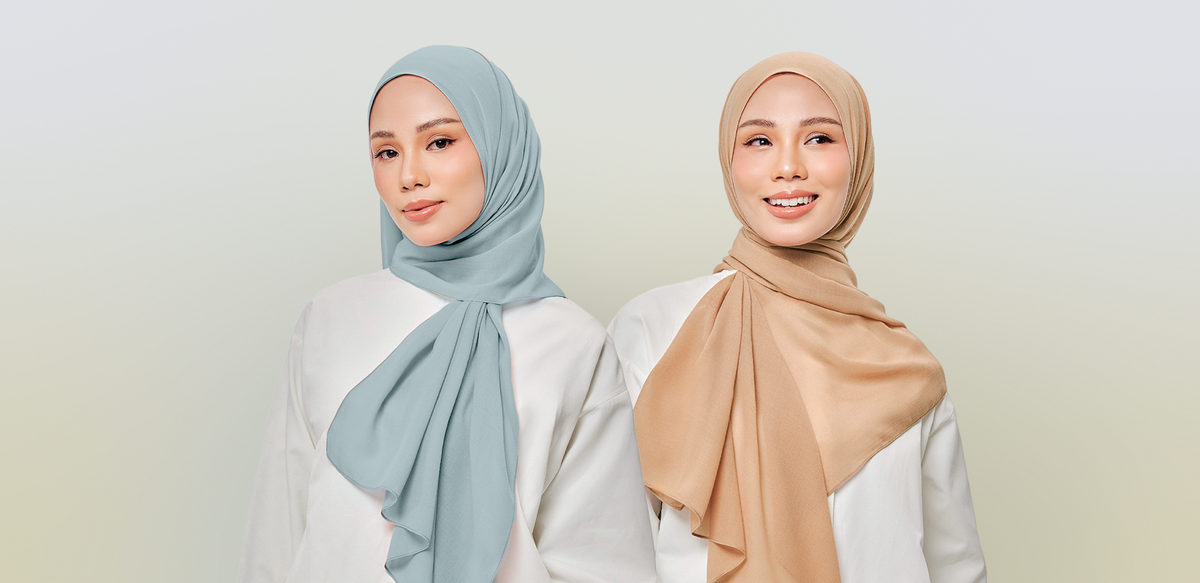 Two smiling women in chiffon shawls, one sage blue and one caramel, both wearing white tops